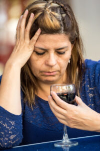 Mature woman very sad looking at her wineglass